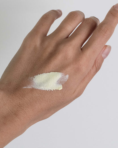 Hand with a small amount of sunscreen on a plain background