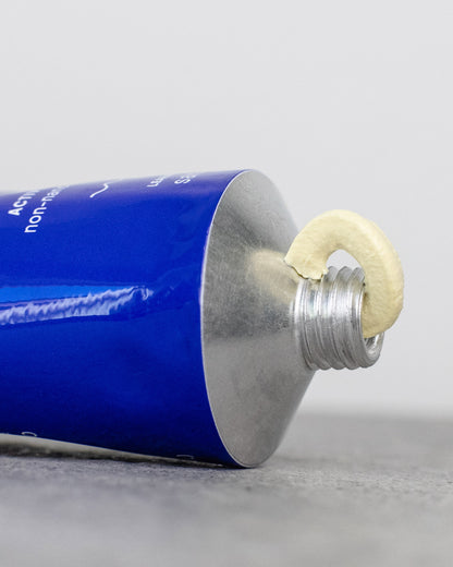 Close-up of BODY sunscreen tube with product squeezed out on gray background